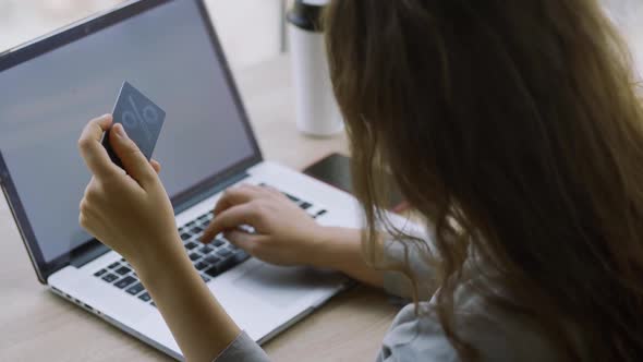 Woman Holds Credit Card Using Laptop at Table