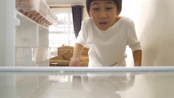 Asian boy was disappointed and sad when opening the empty refrigerator