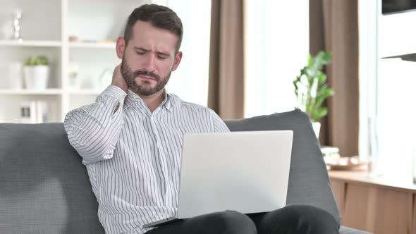 Tired Young Businessman with Laptop Having Neck Pain at Home  alt