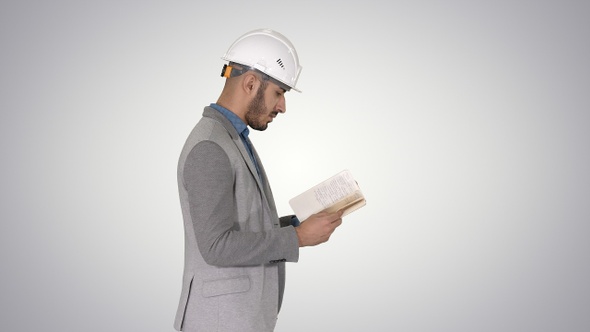 Young architect reading textbook or notebook while walking alt