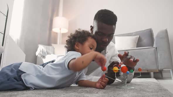 African Family Father and Son Play in the Living Room at Home Man Lying on the Floor with Her Son alt