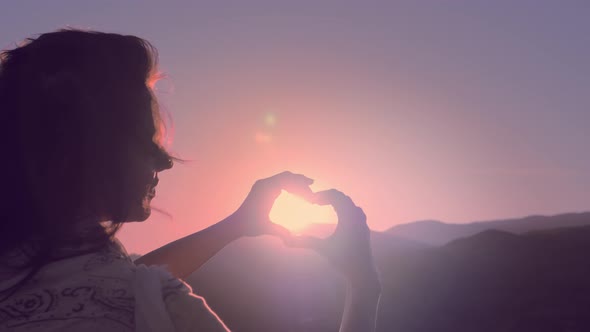 Female Hands in the Form of Heart Against the Sky Pass Sun Beams