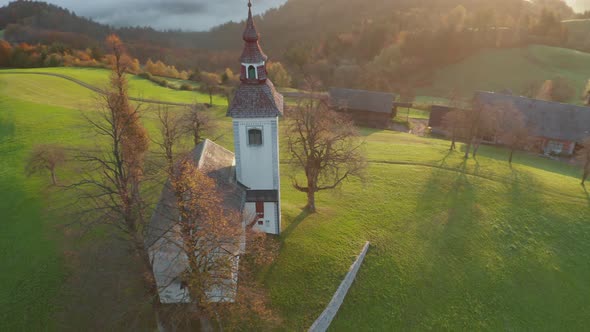 Aerial View of the Hills, Colorful Forest in the Fog and the Church of Sv Tomaz, Sunrise in Slovenia