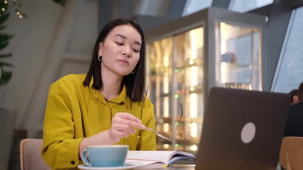 Young Asian Woman Suffering From Eye Strain Taking Off Her Eyeglasses Tired From Working on Computer alt