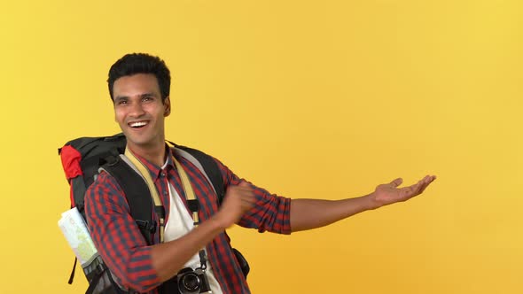 Young indian tourist man with backpack doing open hand gesture and giving thumbs up