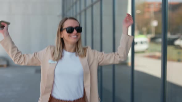 Happy Business Woman with Mobile Dancing Near Office Center alt