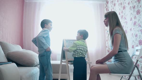 Mother Teaches Little Son To Write the Figures alt