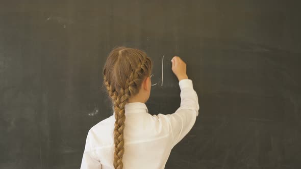 Portrait of a Pretty Girl Writing 'Back to School' on the Blackboard