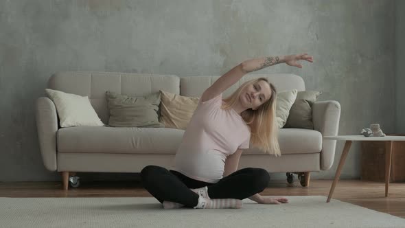 Healthy pregnant female makes bends inside room.