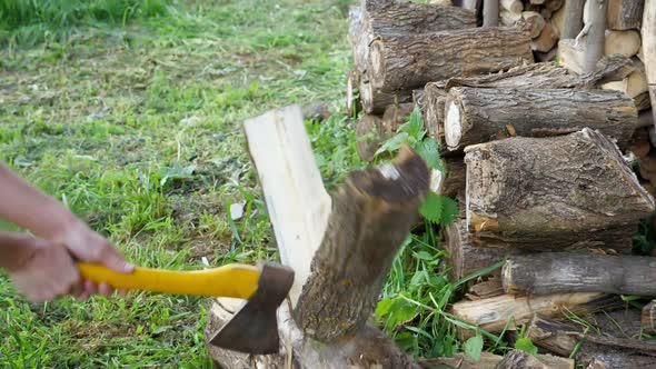 Unrecognizable Man Chopping Wood with an Ax with a Yellow Handle. Slow Motion alt