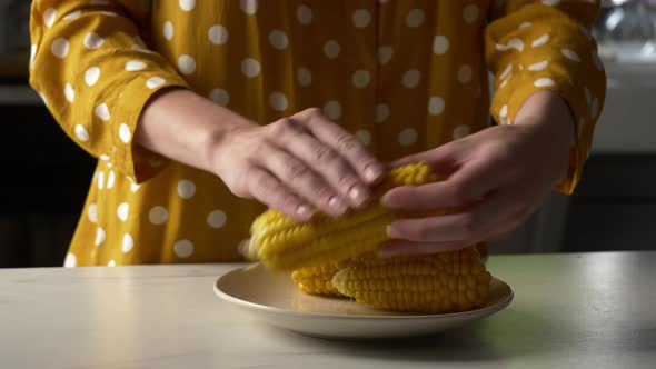 woman rubs salt on corn at kitchen alt
