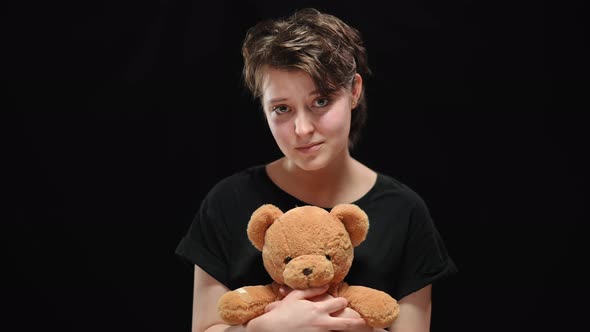 Young Brunette Woman with Sad Smile Holding Teddy Bear Looking at Camera alt