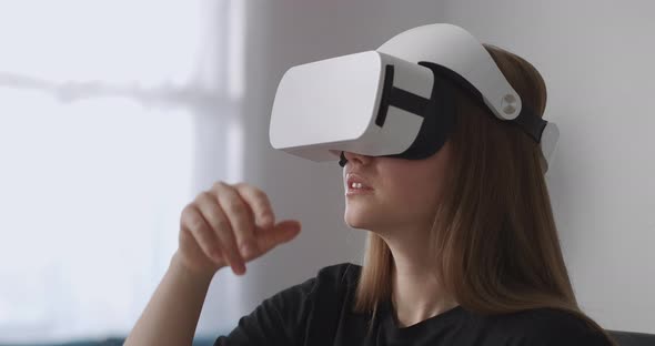 Female User Is Using New Headmounted Display for Playing Games Sitting in Living Room and Moving alt