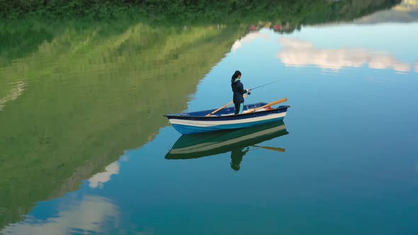 Woman on the Boat Catches a Fish on Spinning in Norway alt