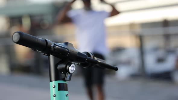 Man walking towards his e-scooter alt