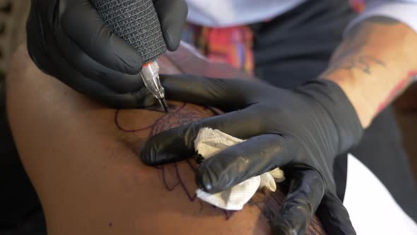 A Tattoo Artist Is Vary Careful For Finishing The Tattoo Art Design That He Made On His Client's Leg alt