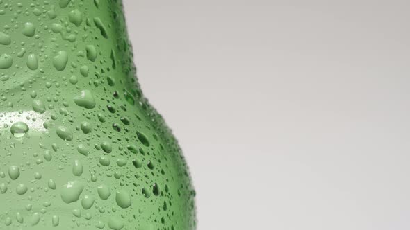 Drop rolls down over a neck of cold green bottle