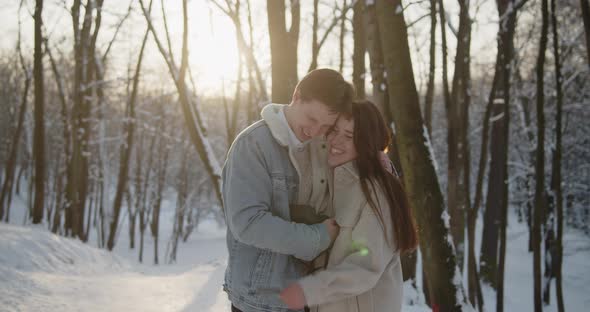 Happy Young Beautiful Couple Spend Time in Sunny Winter Forest Together