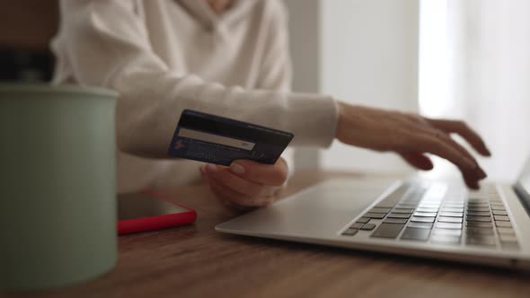 Irritated Young Caucasian Girl Sitting with Computer and Credit Card on Couch in Kitchen Room Can alt