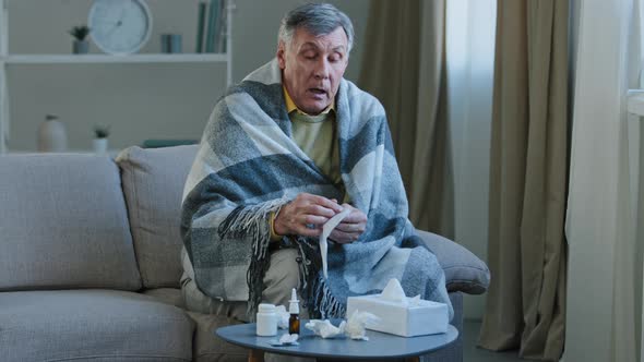Sick Elderly Man Covered with Warm Blanket Suffer From Runny Nose Sneezes in Napkin Unwell Old alt