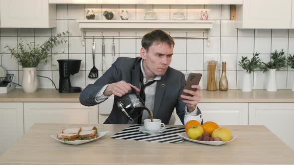 Man Pouring Coffee While Using Smartphone at Home alt