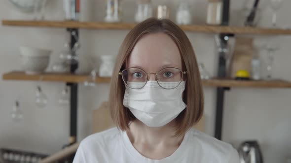 A Young Woman in a Protective Medical Mask Glasses a White Tshirt with a Short Haircut with Books in