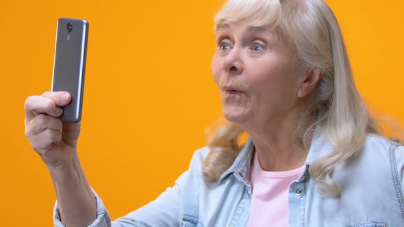 Senior Woman Taking Selfie by Smartphone, Making Foolish Faces, Having Fun alt