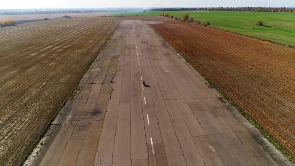 A Motorcycle with Riders of a Man and a Woman Rides at Speed on the Old Runway