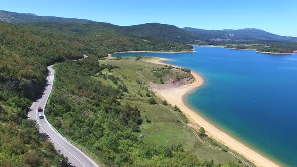 Aerial view of paved road passing artificial lake of Peruca, Croatia alt