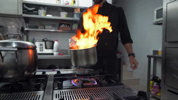 Chef with pot of flames in traditional restaurant kitchen