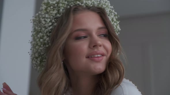 Beautiful Girl in a Wreath of Gypsophila Looks at the Camera alt