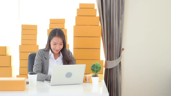 Young Asian entrepreneur girl sitting by the desk with laptop selling online alt