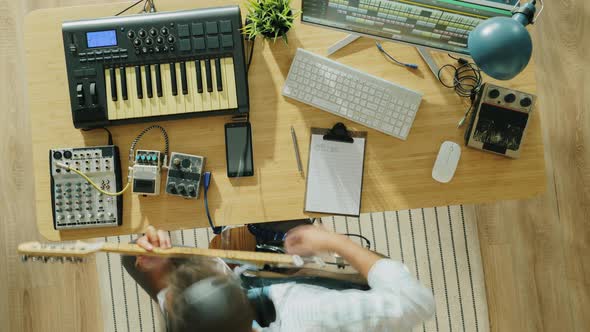 Top View Time Lapse of Young Man Creating Music Playing Keyboard and Guitar at Home alt