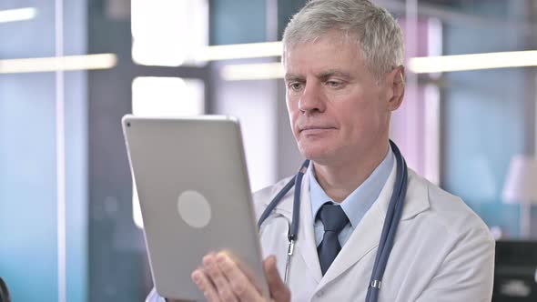 Portrait of Middle Aged Doctor Scrolling on Tablet alt