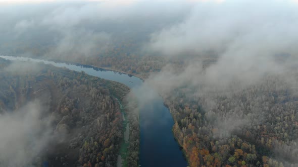 Low-lying Clouds Over an Evergreen Forest with a River. Fog Over the Jungle alt