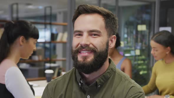 Portrait of happy caucasian businessman over diverse business colleagues discussing alt