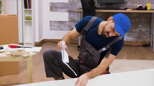 Confused Worker in Overalls Reading Instructions alt