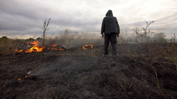 man walks on a burning field in the steppe alt