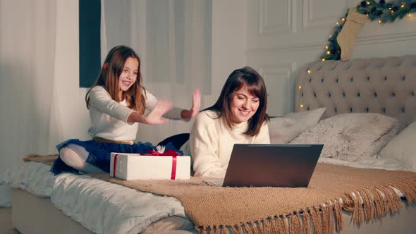 Mother and Child Communicate Remotely with Their Father Through Laptop Video Communication alt