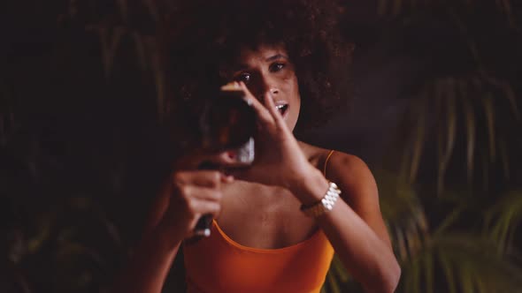 Woman With Afro Hair In Orange Dress Using Vintage 8Mm Camera alt