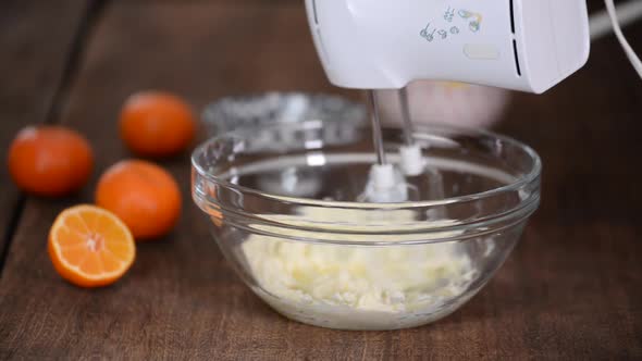 Mixing butter and sugar in bowl with mixing machine.