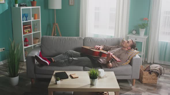 Young Man Is Relaxing By Playing Guitar alt