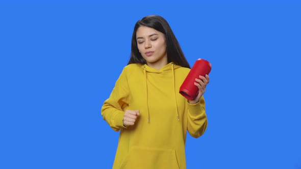 Portrait of Brunette Listening to Music with Bluetooth Portable Speaker and Dancing alt