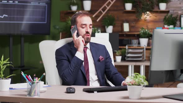 In Modern Office, After Work Hours, a Businessman Is Talking on the Phone alt