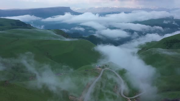 Aerial view on the  green fields at the mountains in the clouds and fog