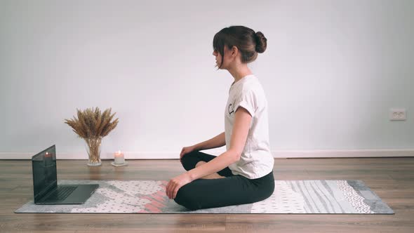 Caucasian Woman Does Yoga Online A Woman Sits in a Lotus Position and Does Breathing Exercises Yoga