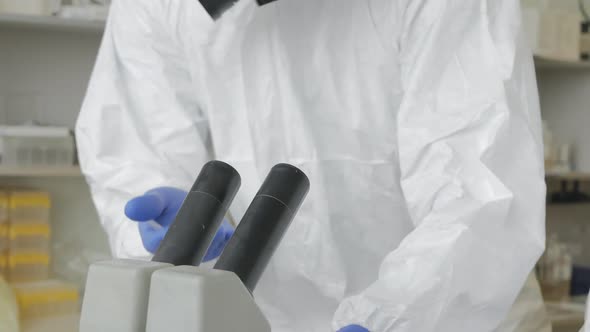 Virologist Scientists a Man and a Woman Take Turns Looking Through a Microscope Discussing and alt