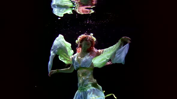 Female Figure Underwater in Darkness, Woman Is Keeping Afloat and Moving Hands, Slow Motion alt