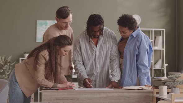 Multiethnic Team of Renewable Energy Engineers Discussing Blueprint alt