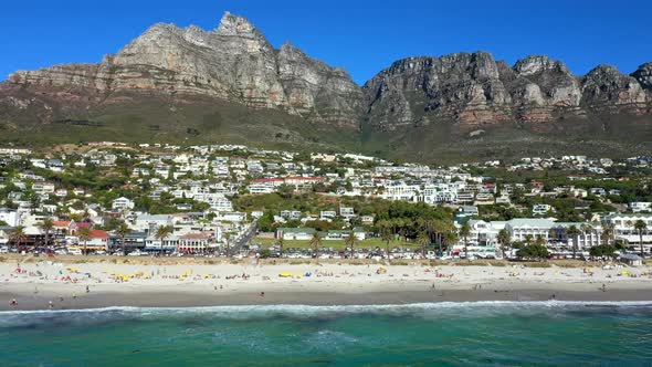 Wide side tracking shot showcasing the entire length of Camps Bay beach